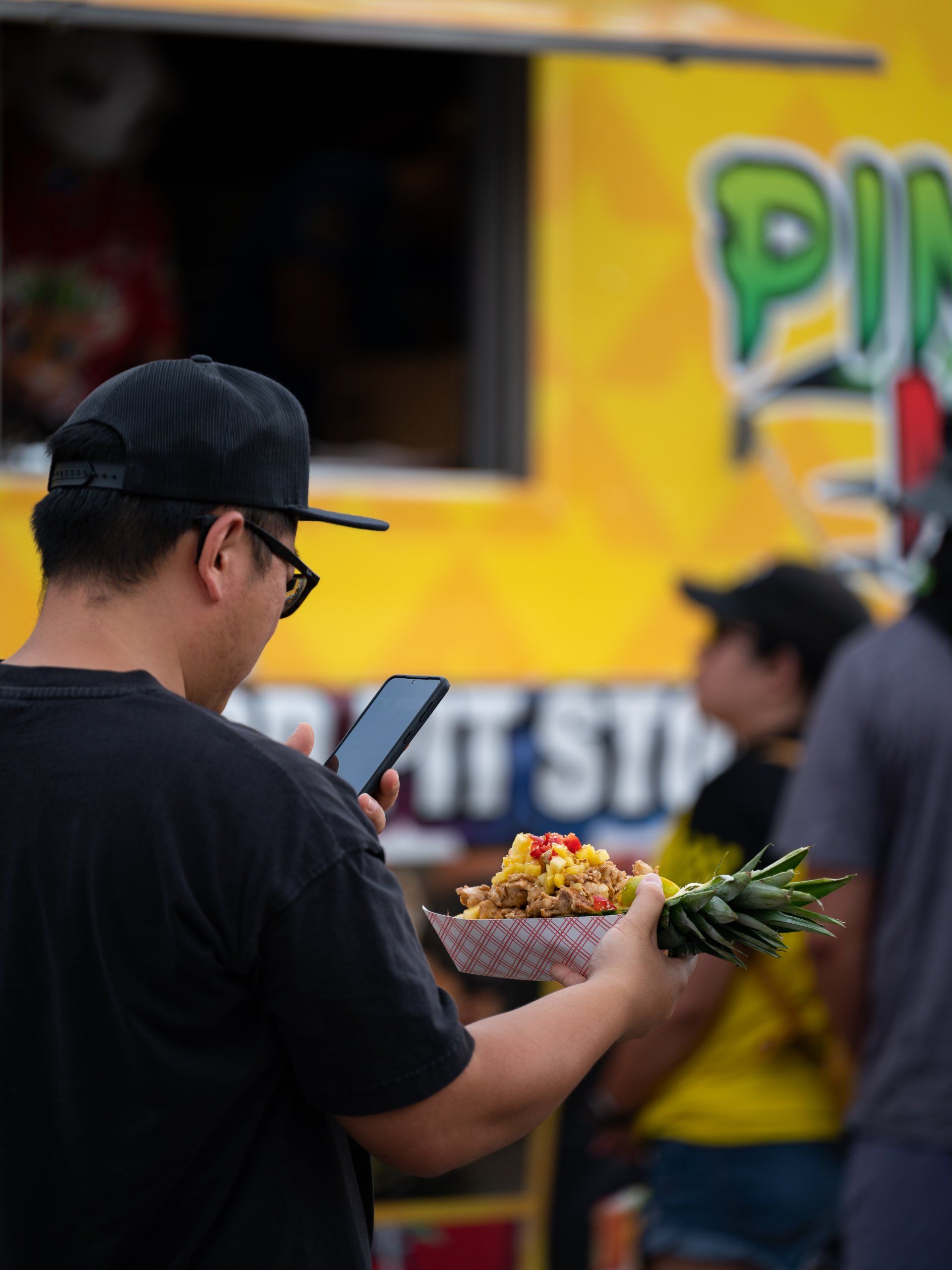 The bright-yellow Pineapple Ninjaz truck with a customer holding a pineapple bowl